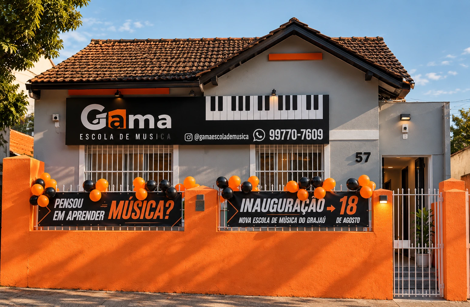 Fachada real da Gama Escola de Música, com muro laranja e placa preta, na Rua Uberaba, 57